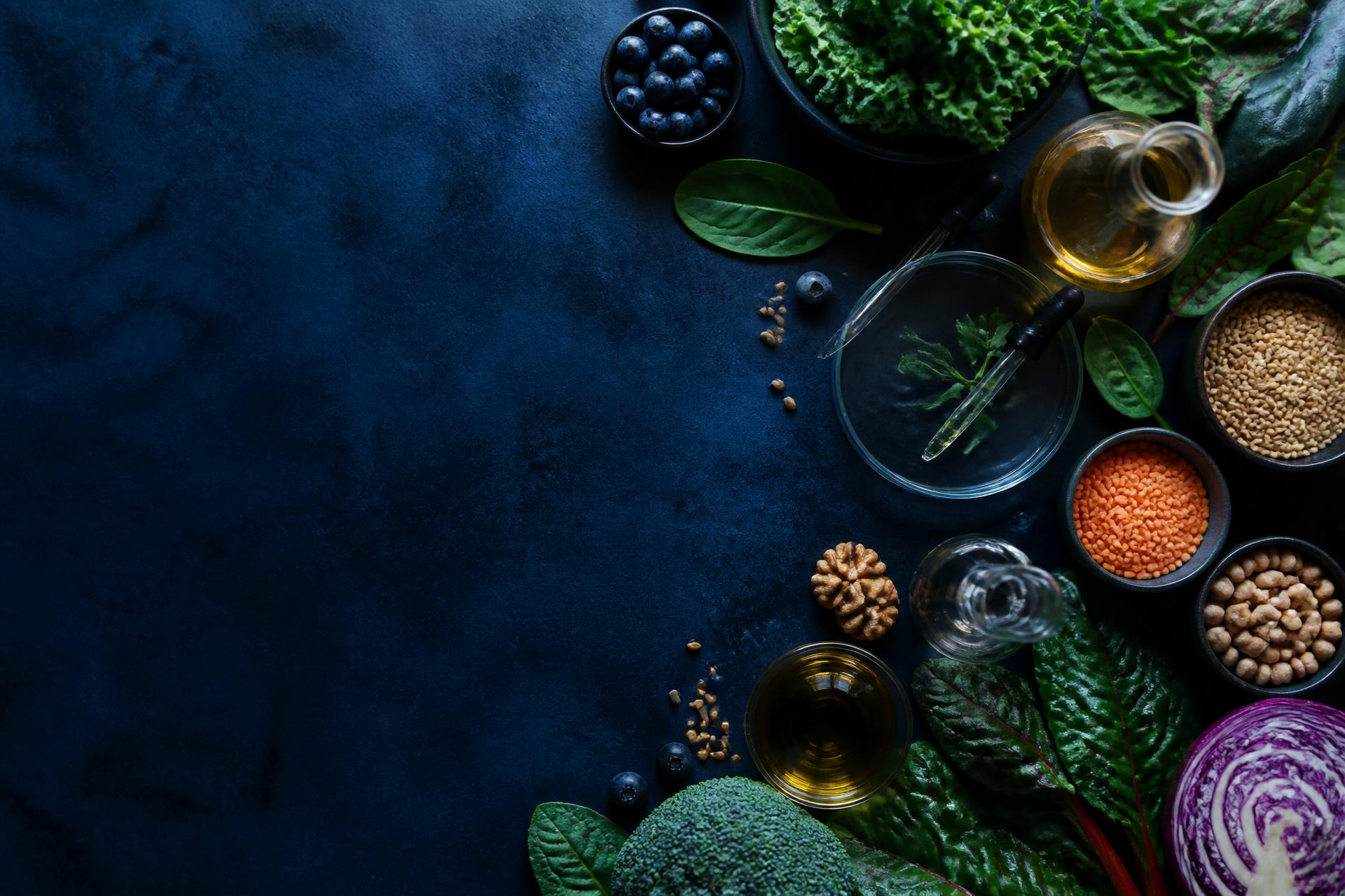 Whole foods and laboratory glassware arranged on a dark surface